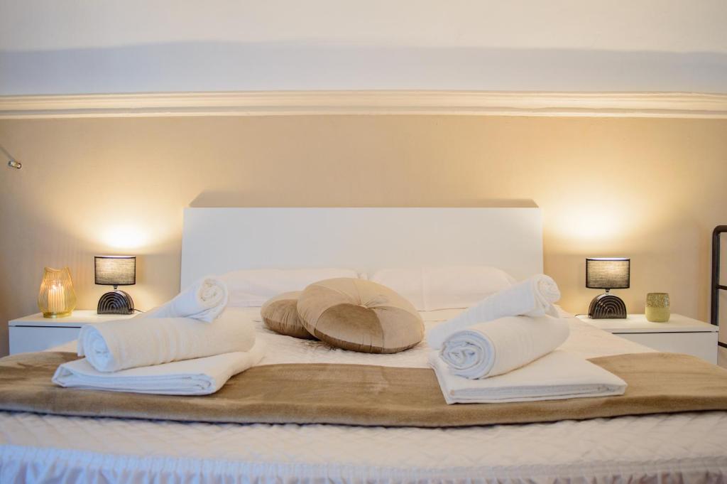 Una cama blanca con toallas y almohadas. en Esclusivo Loft Centro Storico private garden E-Bike, en Cherasco