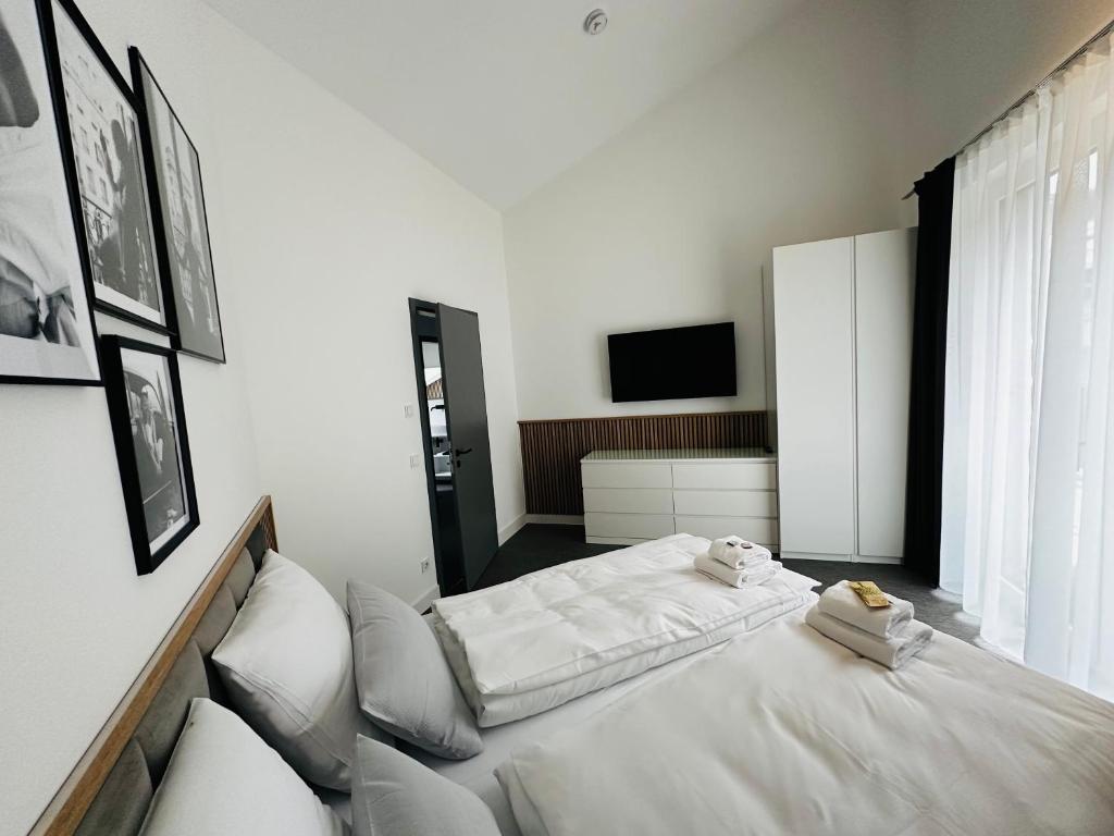Habitación blanca con 2 camas y TV en GreenLeaf Regensburg I Sinzing, en Sinzing