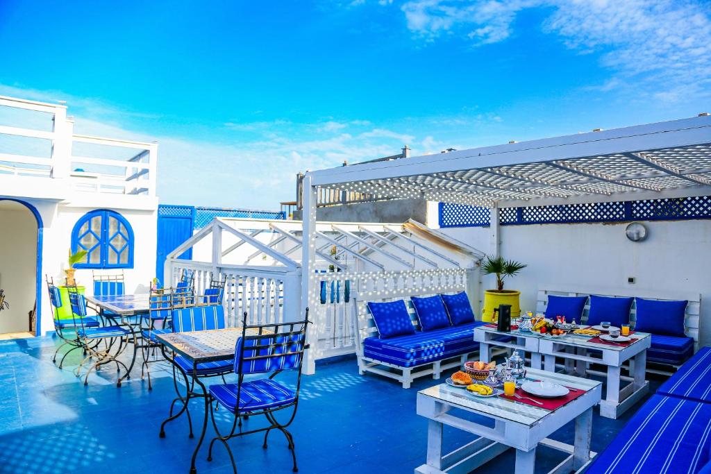eine Terrasse mit blauen Stühlen und Tischen auf dem Balkon in der Unterkunft Dar Nafoura-Mogador in Essaouira