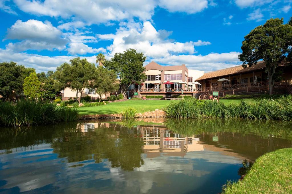 a house with a pond in front of it at Glenburn Lodge & Spa in Muldersdrift