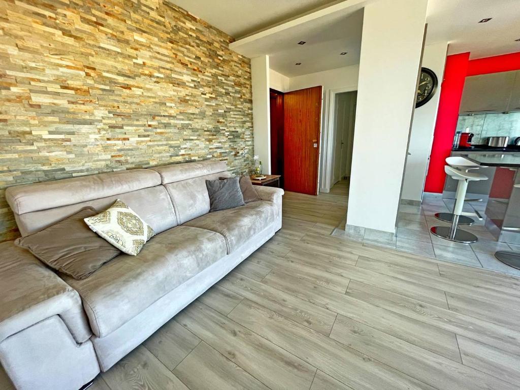 a living room with a couch and a brick wall at Le Chaville in Cagnes-sur-Mer