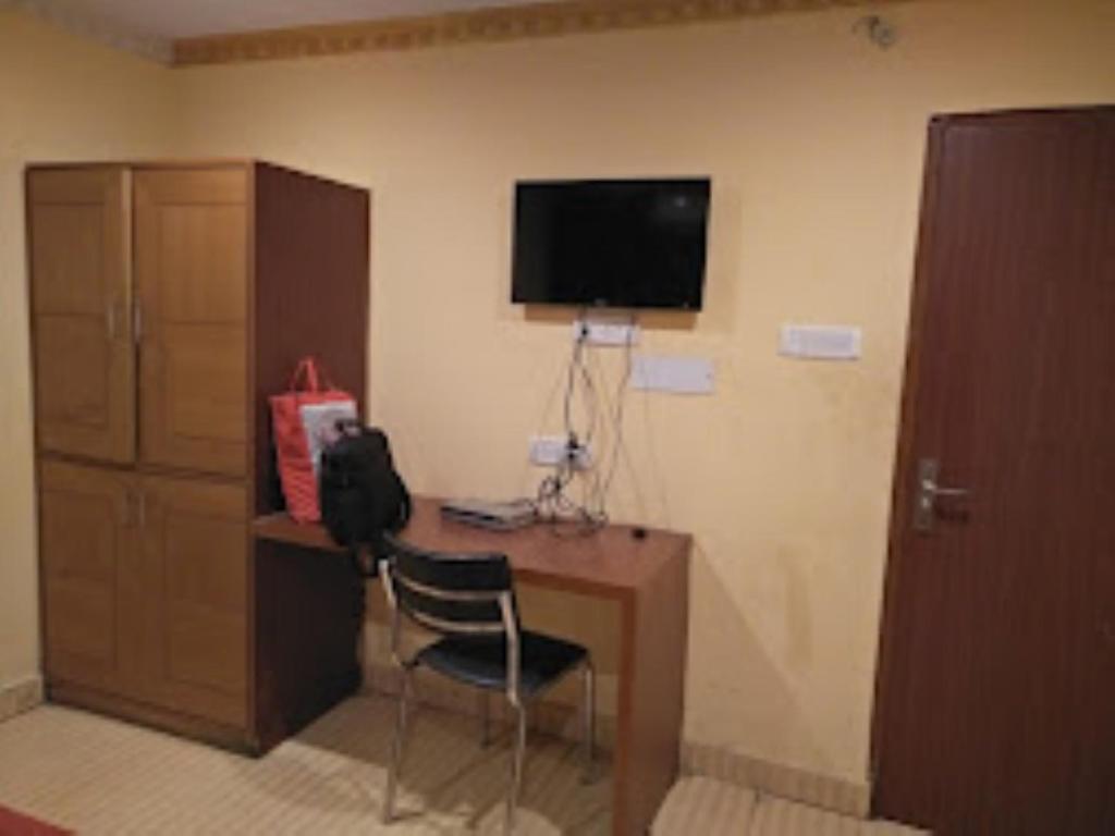 Bapu Guest House,Bhubaneswar في بوهفانيشفار: غرفة بها مكتب مع كرسي وتلفزيون
