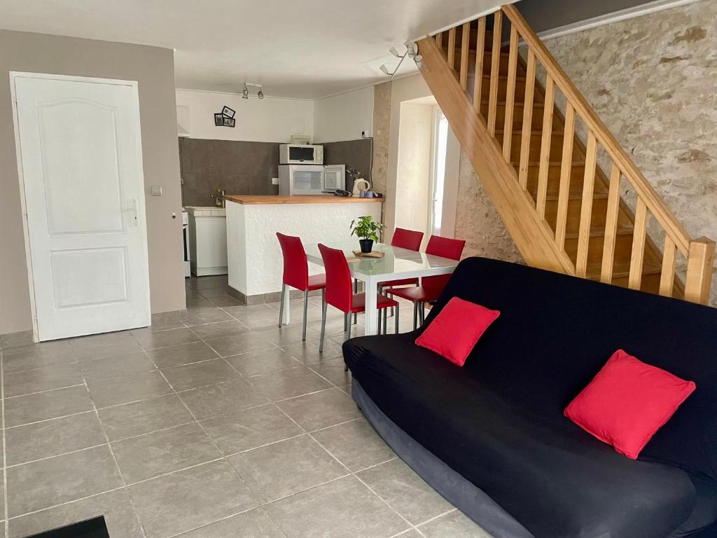 - un salon avec un canapé et une table avec des oreillers rouges dans l'établissement Les Gîtes de La Vieille Roue - Gite 3, à Reignac