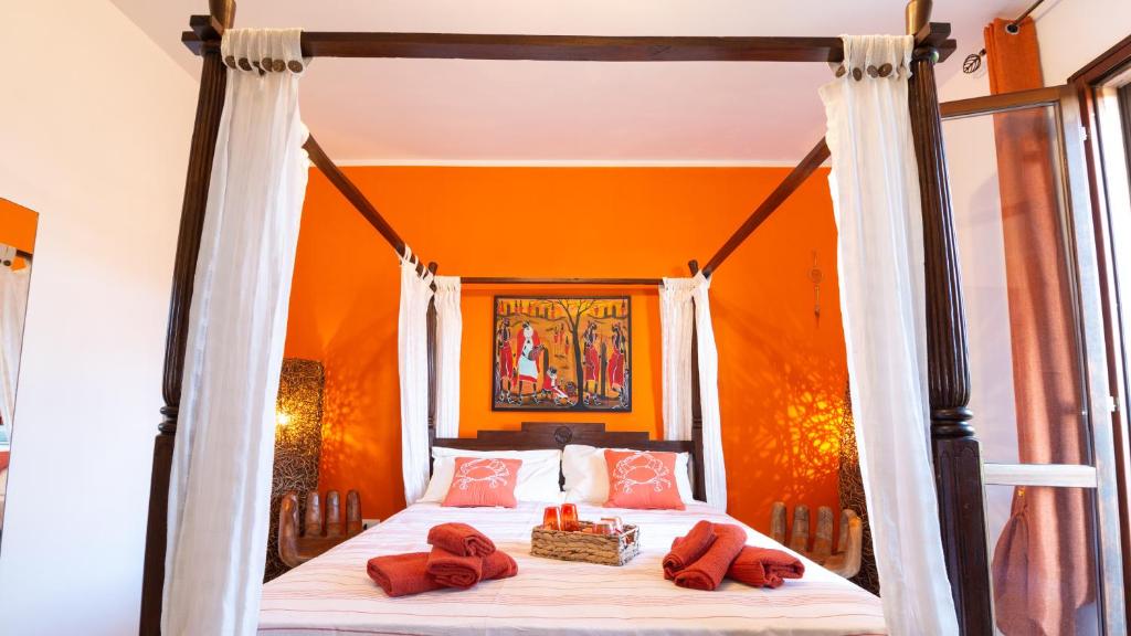 Un dormitorio naranja con una cama con almohadas rojas. en Ben House, en Santa Giusta