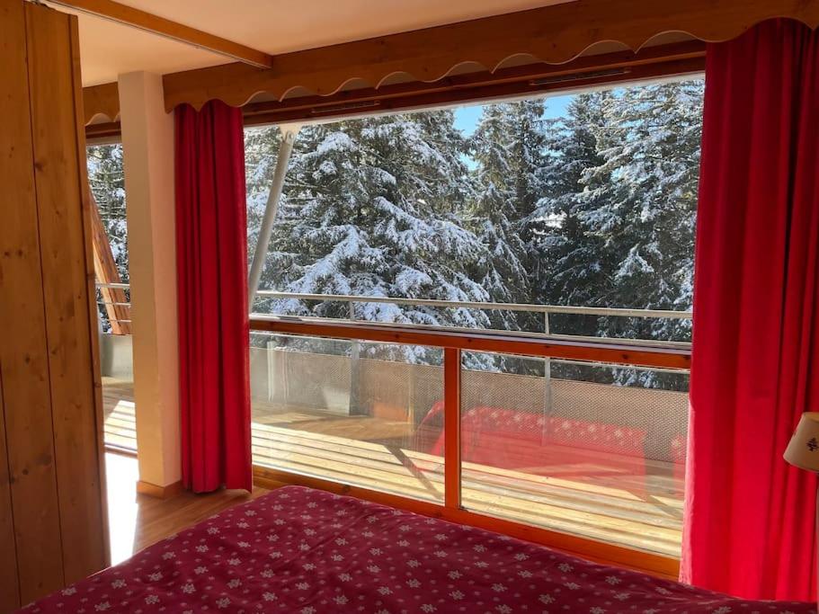 1 dormitorio con ventana grande con árboles nevados en Chamrousse, pied d'une piste, terrasse vue sapins, en Chamrousse