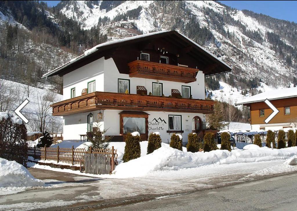 una casa grande en la nieve frente a una montaña en Chalet Charlotte, en Fusch an der Glocknerstrasse
