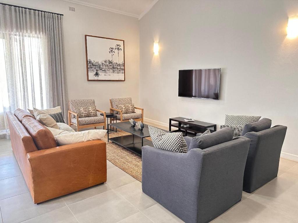 a living room with couches and a flat screen tv at Narina Villa in Victoria Falls