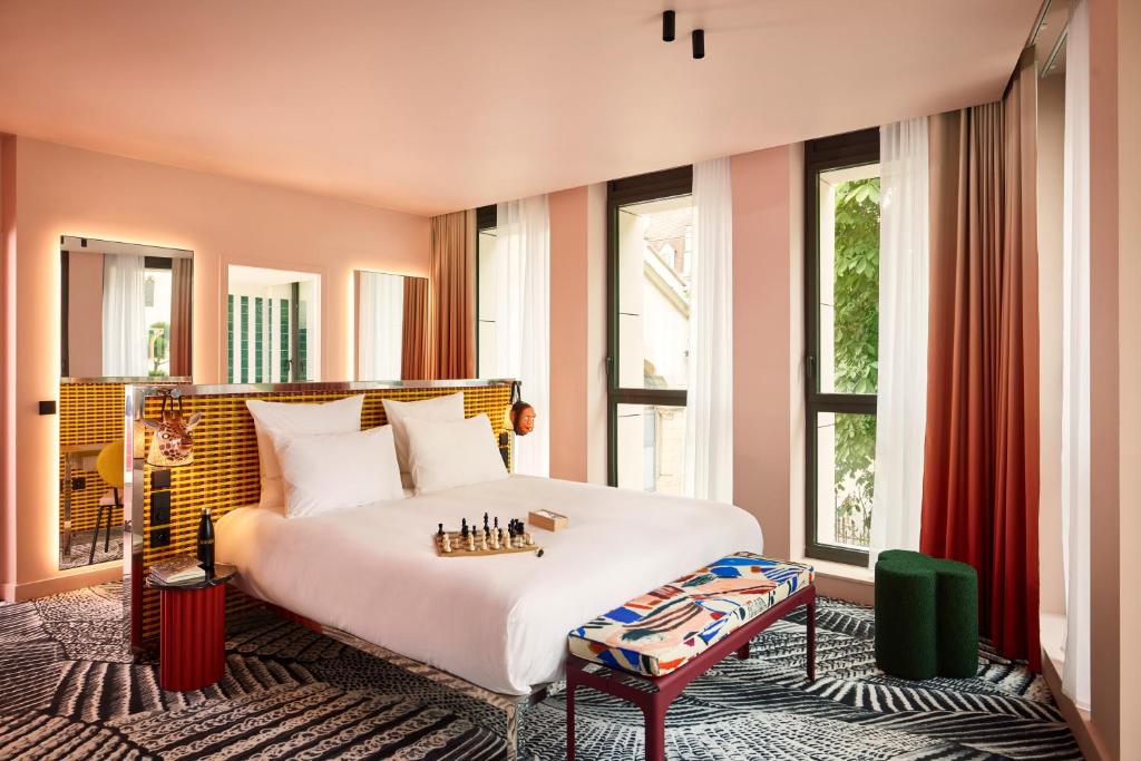 une chambre avec un grand lit blanc et des fenêtres dans l'établissement Mama Shelter Dijon, à Dijon