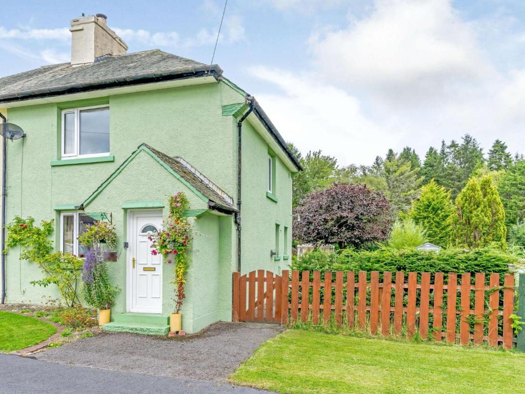 a green house with a wooden fence at 2 Bed in Kielder 89299 in Falstone