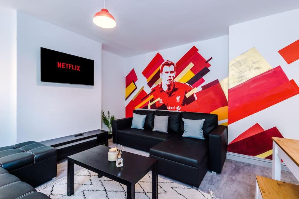 a living room with a black couch and a painting at 5 Sleeper LFC Themed Apartment in Liverpool