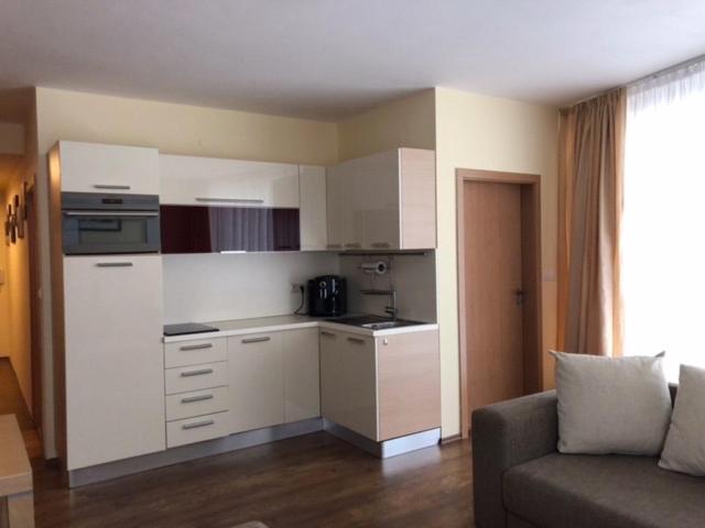 una cucina con armadi bianchi e un soggiorno con divano. di Apartman priamo na svahu a Donovaly