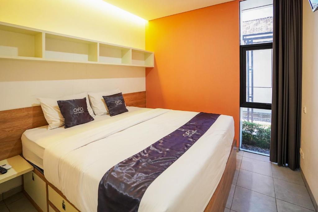 Pare的住宿－OFO Kost Premium Kampung Inggris Pare Syariah Mitra RedDoorz，一间卧室配有一张带橙色墙壁的大床