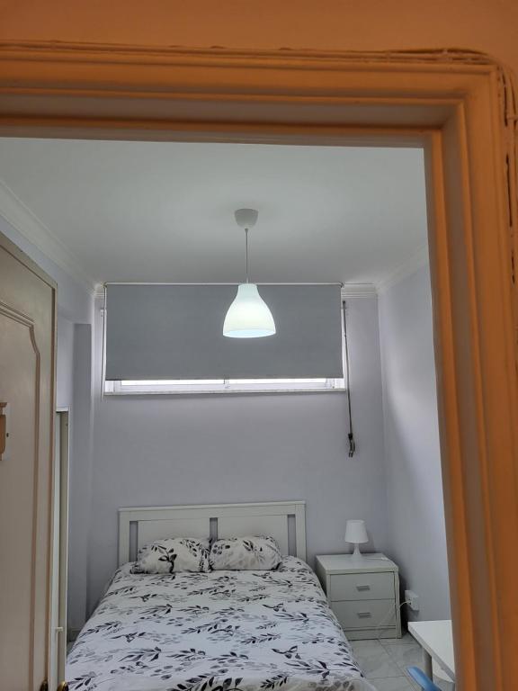 a white bedroom with a bed with a window at K House in Odivelas