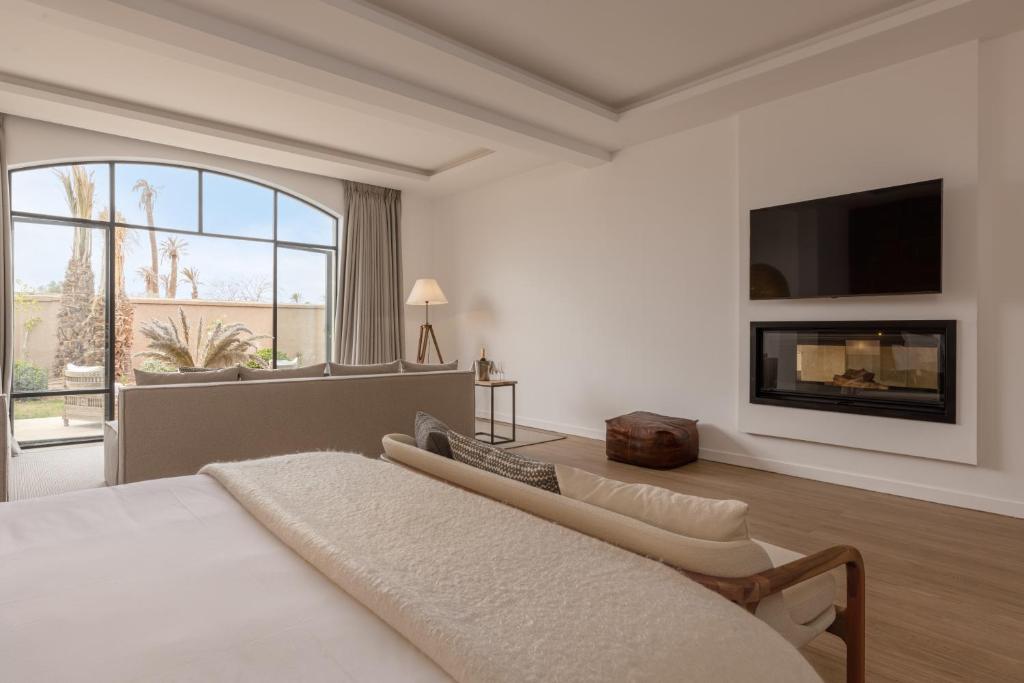 a white bedroom with a bed and a fireplace at Ksar Char-Bagh Small Luxury Hotels in Marrakesh