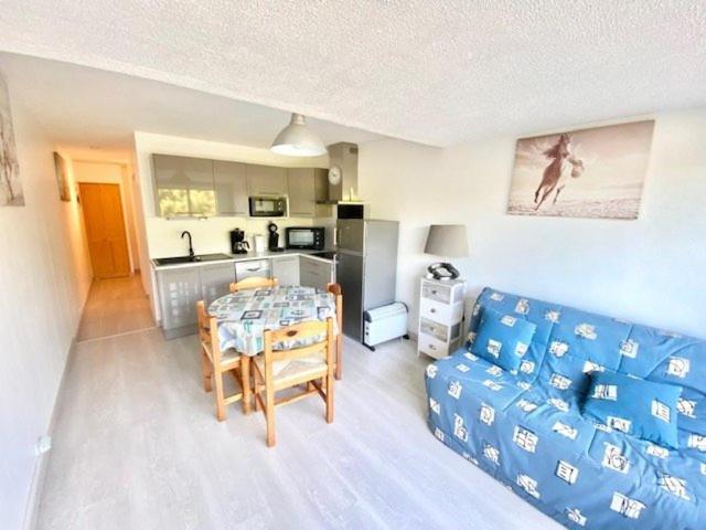 un salon avec une table et un canapé bleu dans l'établissement studio cabine 4 pers proche des plages, au Grau-du-Roi