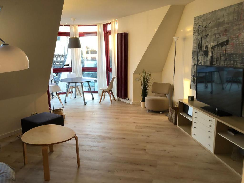 ein Wohnzimmer mit einem TV, einem Tisch und Stühlen in der Unterkunft Stilvolle helle Wohnung im Zentrum in Osnabrück