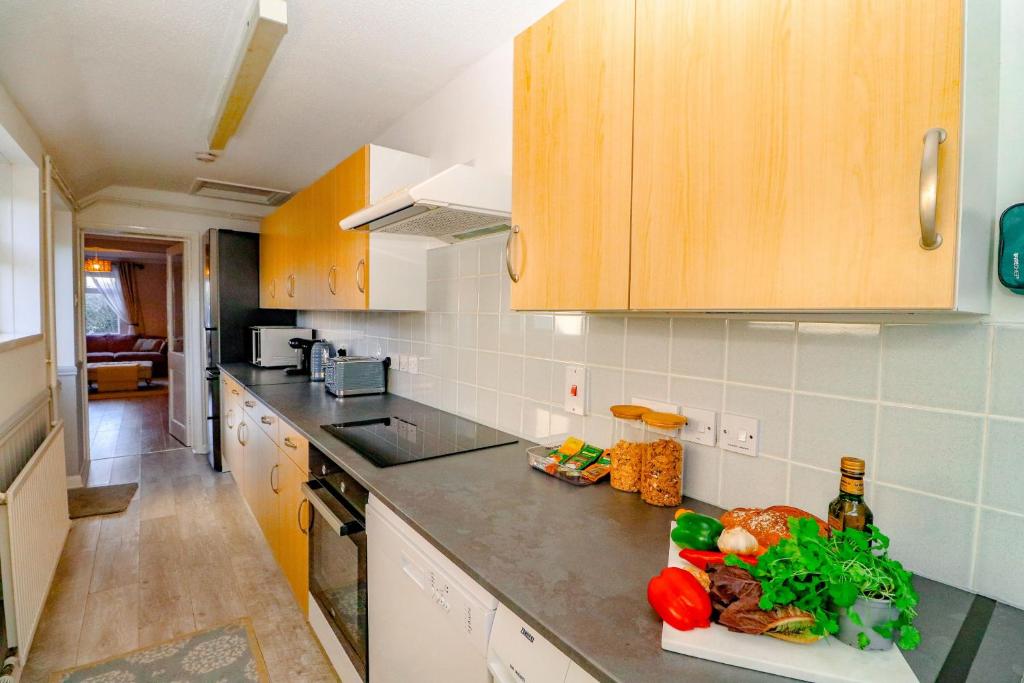 una cocina con armarios de madera y verduras en la encimera en Country View Cottage, en Halvergate