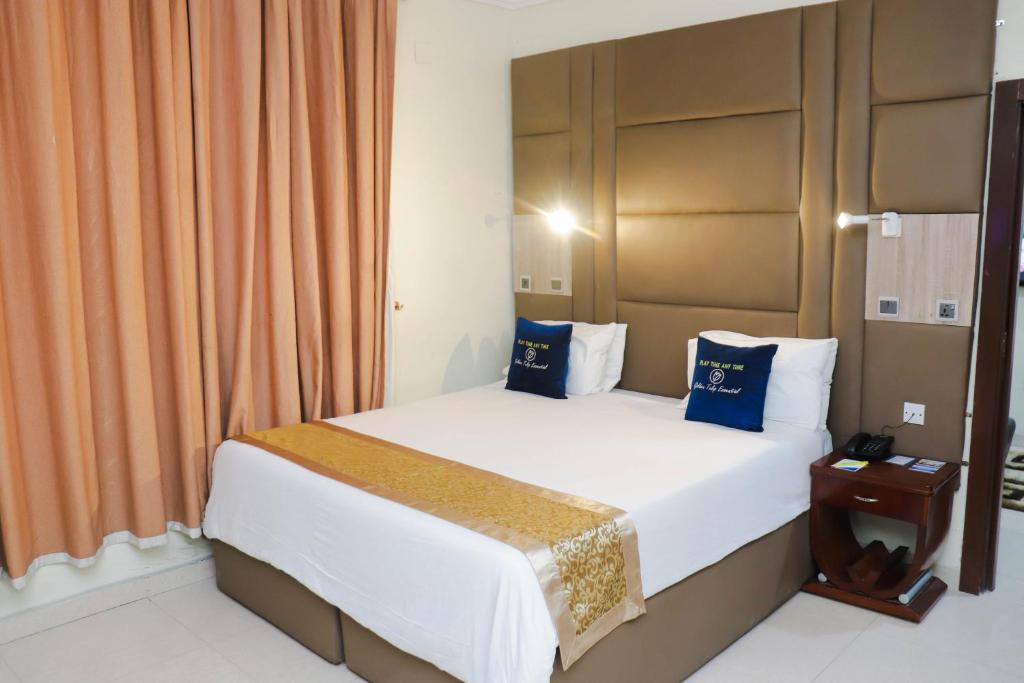 a bedroom with a large bed with blue pillows at Golden Tulip Hotel- Evergreen Port Harcourt in Port Harcourt
