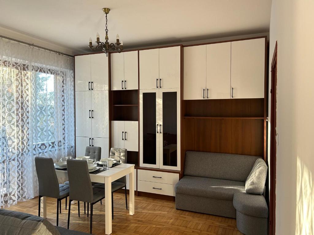 ein Wohnzimmer mit einem Tisch, einem Stuhl und einem Sofa in der Unterkunft Apartament Ludźmierska Nowy Targ in Nowy Targ