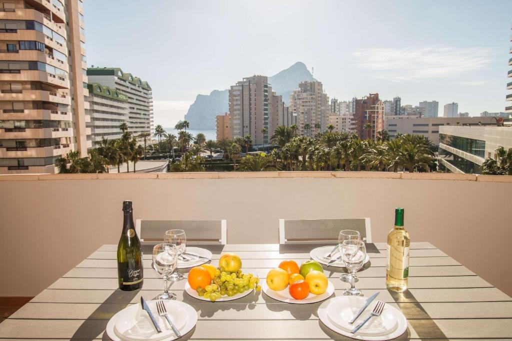 un tavolo con piatti di frutta e bottiglie di vino di Apartamento Coral Beach - PlusHolidays a Calpe