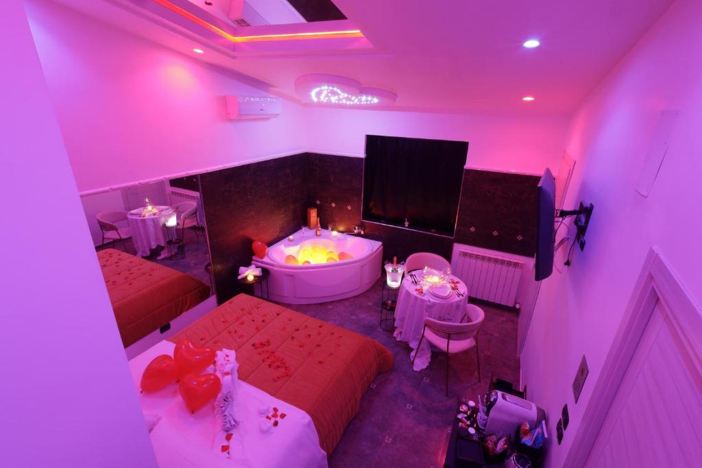 Camera rosa con vasca, letto e tavoli di B&B GRECALE Suite & Spa a Rende