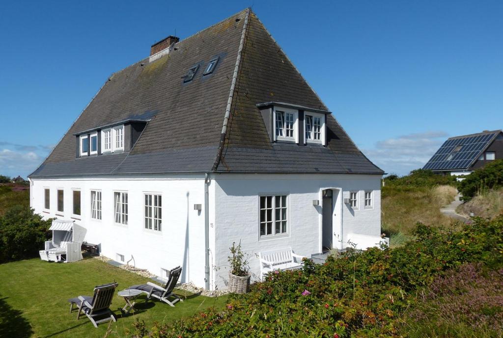 una casa blanca con techo en una colina en Haidewai, en Hörnum