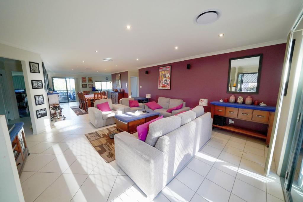 uma sala de estar com mobiliário branco e paredes roxas em Quay Largo em Lake Tabourie