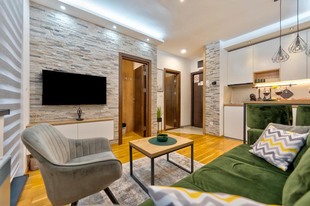 ein Wohnzimmer mit einer Couch und einem Fernseher an einer Ziegelwand in der Unterkunft Durmitor 64 - Titova vila in Zlatibor