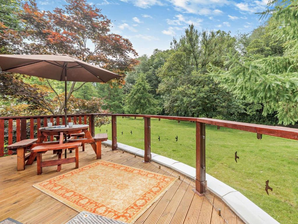 a wooden deck with a picnic table and an umbrella at 3 Bed in Cockermouth 49198 in Cockermouth