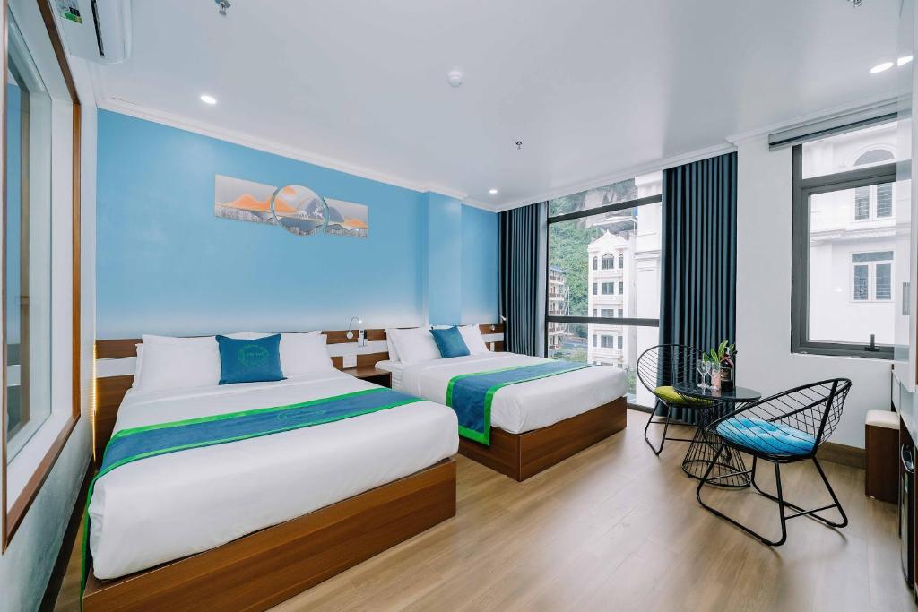 sypialnia z 2 łóżkami i niebieską ścianą w obiekcie TOMMY HOTEL w mieście Cát Bà