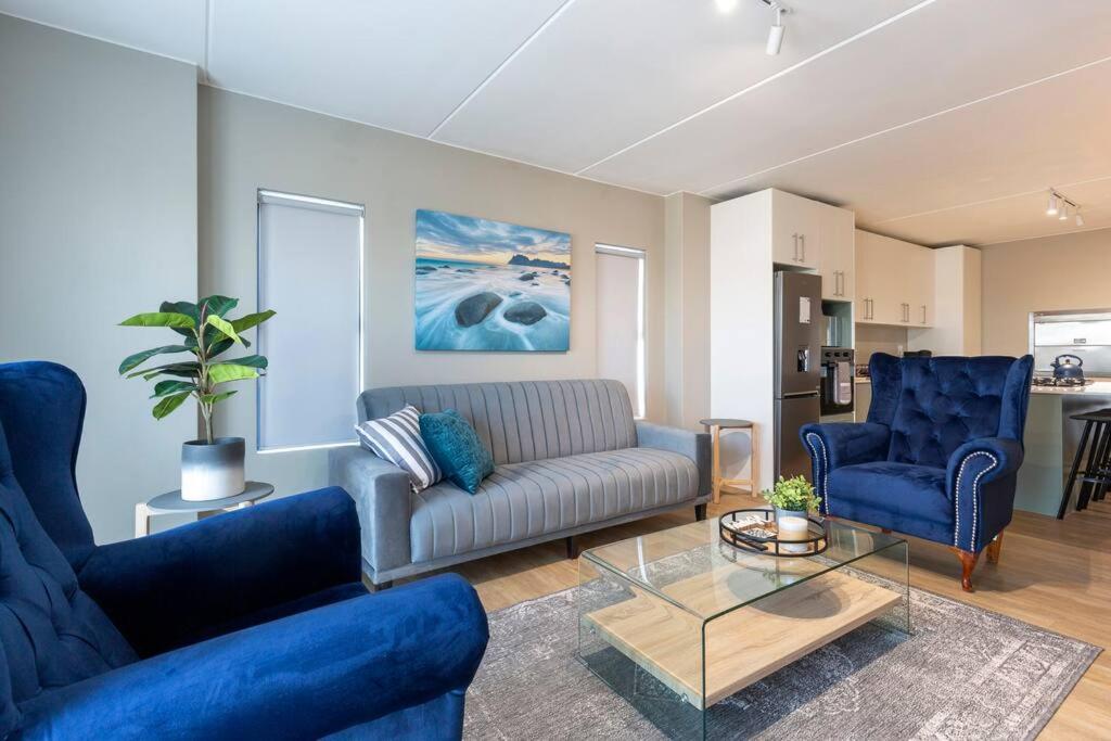 a living room with a couch and two blue chairs at Nivica 56 Luxury Apartment Langebaan in Langebaan