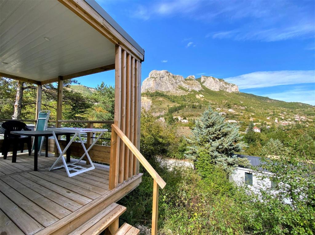 une terrasse en bois avec une table et une vue sur la montagne. dans l&#39;établissement Camping les Princes d&#39;Orange, à Orpierre