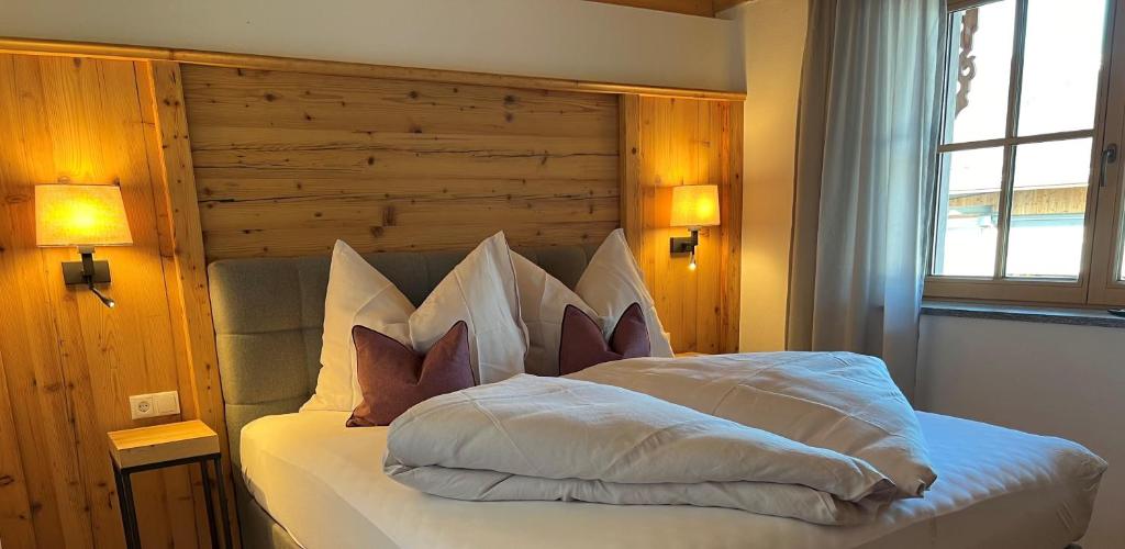 フューゲンにあるLandhaus Huberの白いベッド1台(木製ヘッドボード付)が備わるベッドルーム1室が備わります。