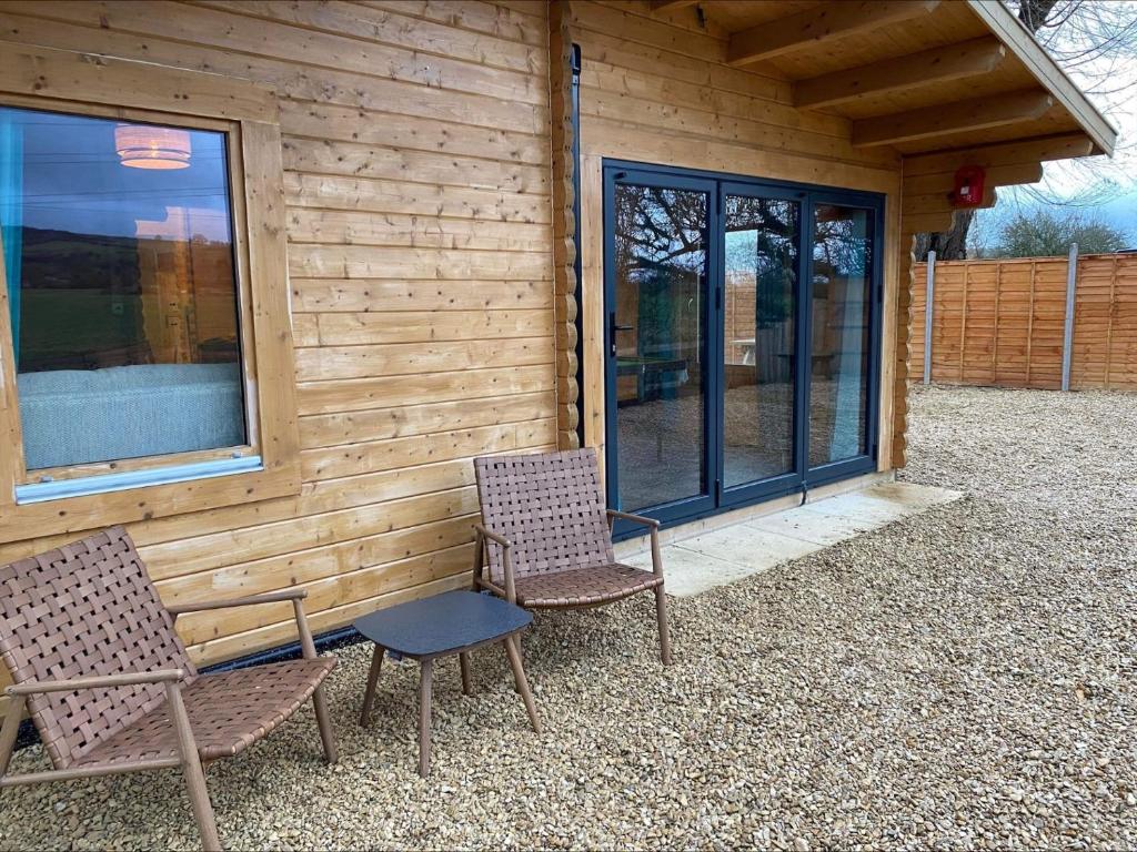 two chairs sitting outside of a building with windows at Inviting 2-Bedroom Cabin in Ashton Under Hill in Evesham