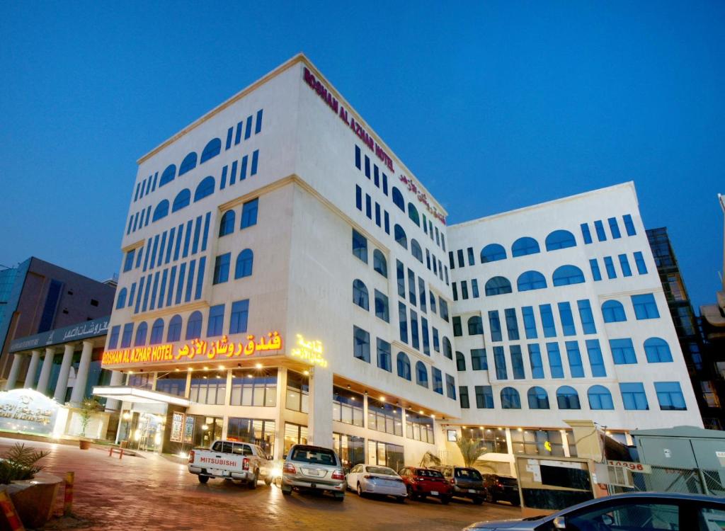 吉達的住宿－羅山艾爾阿扎酒店，一座白色的大建筑,汽车停在停车场