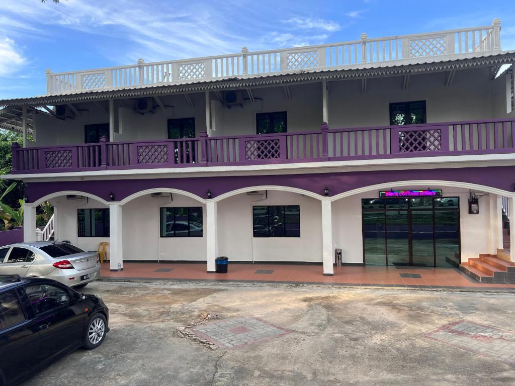 un edificio blanco y púrpura con un coche aparcado en un aparcamiento en OYO 90907 Brick Cottage Homes en Kuah
