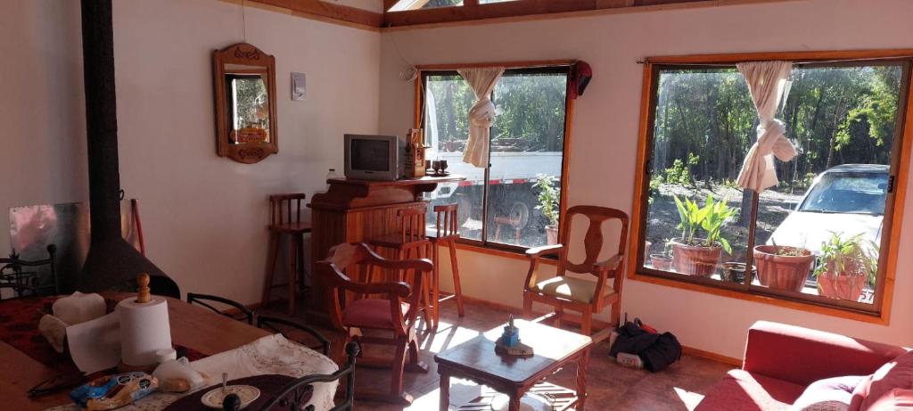 sala de estar con mesa, sillas y ventanas en Casa cerca Radal 7 tazas en Molina