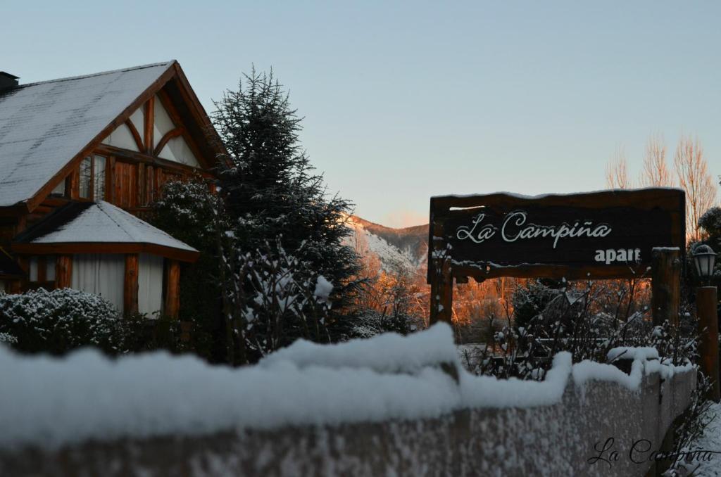 un cartel en la nieve frente a una cabaña en La Campiña en San Carlos de Bariloche