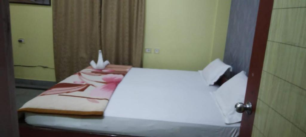 a bedroom with a bed with a white sheets and a mirror at Hotel Swagat in Puri