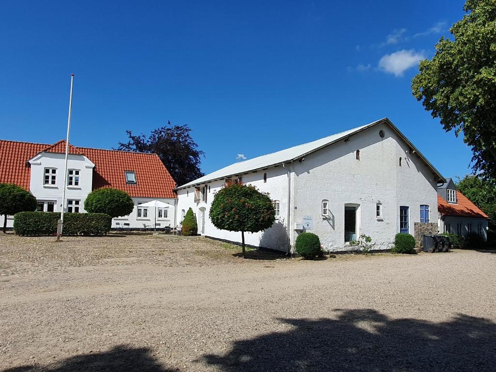 a white building in a yard with two houses at Pension Slotsgaarden jels in Jels