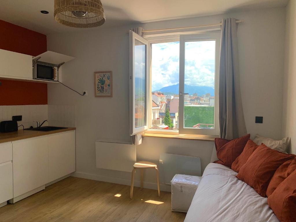 a bedroom with a bed and a kitchen with a window at Le Coucou - Gare - GEM in Grenoble