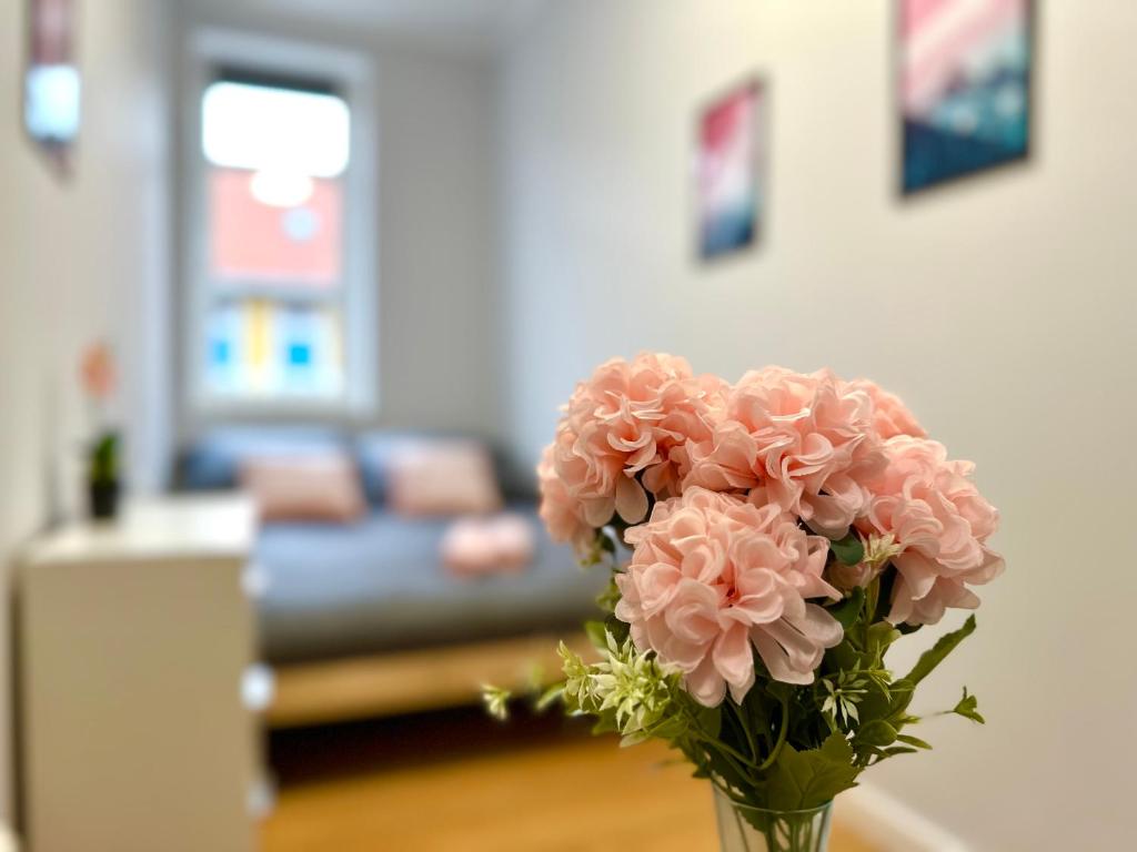 een vaas gevuld met roze bloemen in een woonkamer bij MMRent Pink Room in Gdańsk