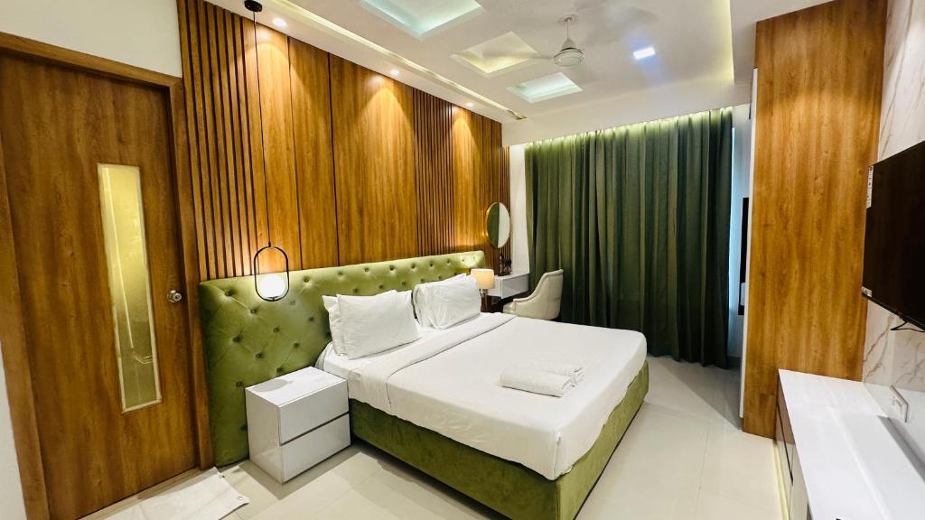 een slaapkamer met een bed met een groene muur bij Hotel Elite Millennium - Near Huda City Centre Gurgaon in Gurgaon