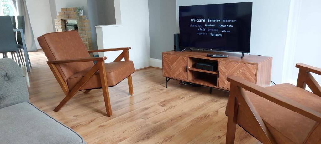 ein Wohnzimmer mit einem Flachbild-TV und einem Stuhl in der Unterkunft LoveLea Properties, House in Wolverhampton in Fallings Park