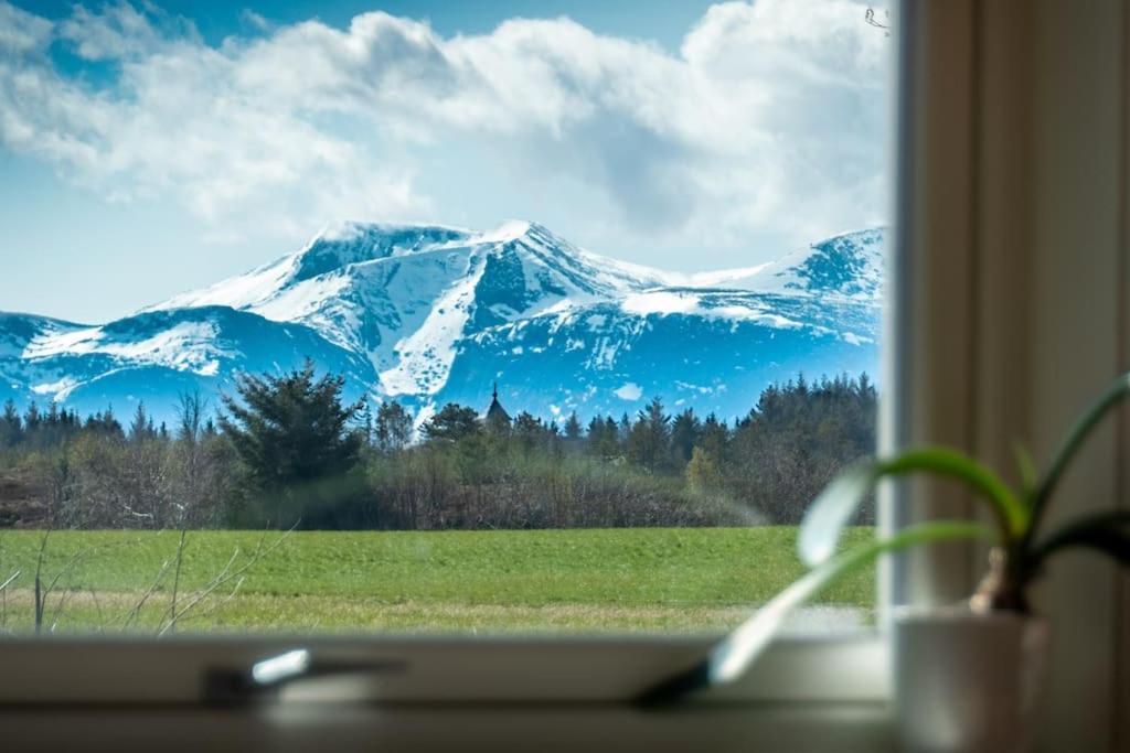 a view of a snow covered mountain through a window at Island Getaway: Sea and Mountain Views in Ålesund