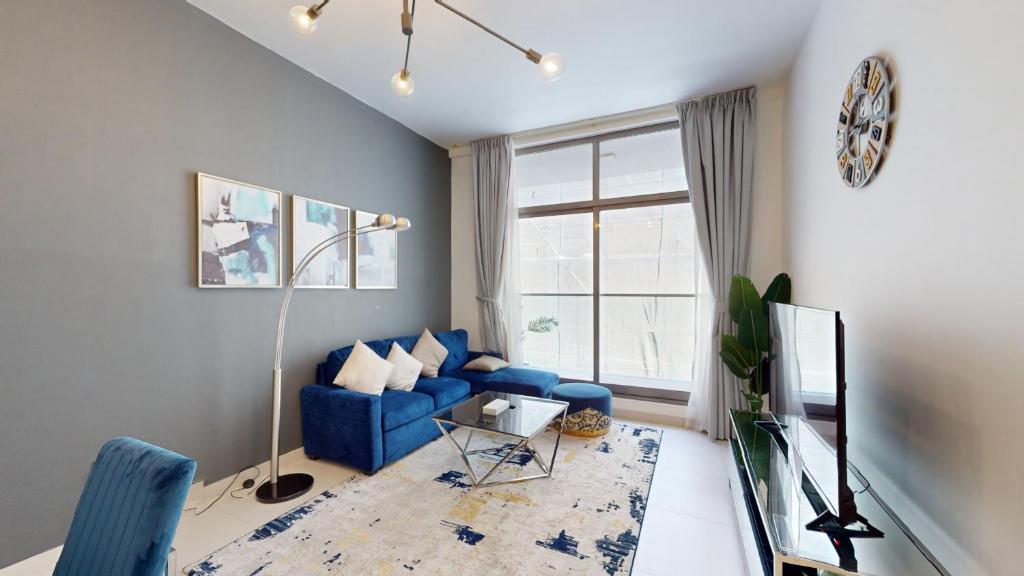uma sala de estar com um sofá azul e uma janela em Primestay - Prime Views 1BR - Meydan em Dubai