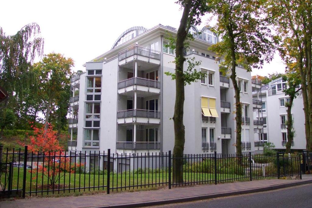 a white building with a fence in front of it at Charmante Fewo mit direktem Strandzugang, Badewanne, Saunabereich im Haus in Heringsdorf