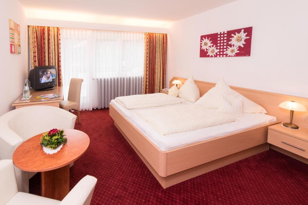 オーベルストドルフにあるホテル ガルニ レジーナのベッドとテーブルが備わるホテルルームです。