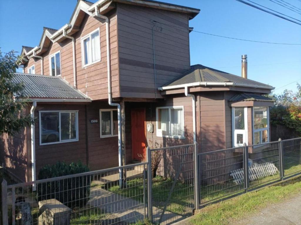 uma casa com uma cerca em frente em EL URCO CHILOE HOSTEL em Ancud