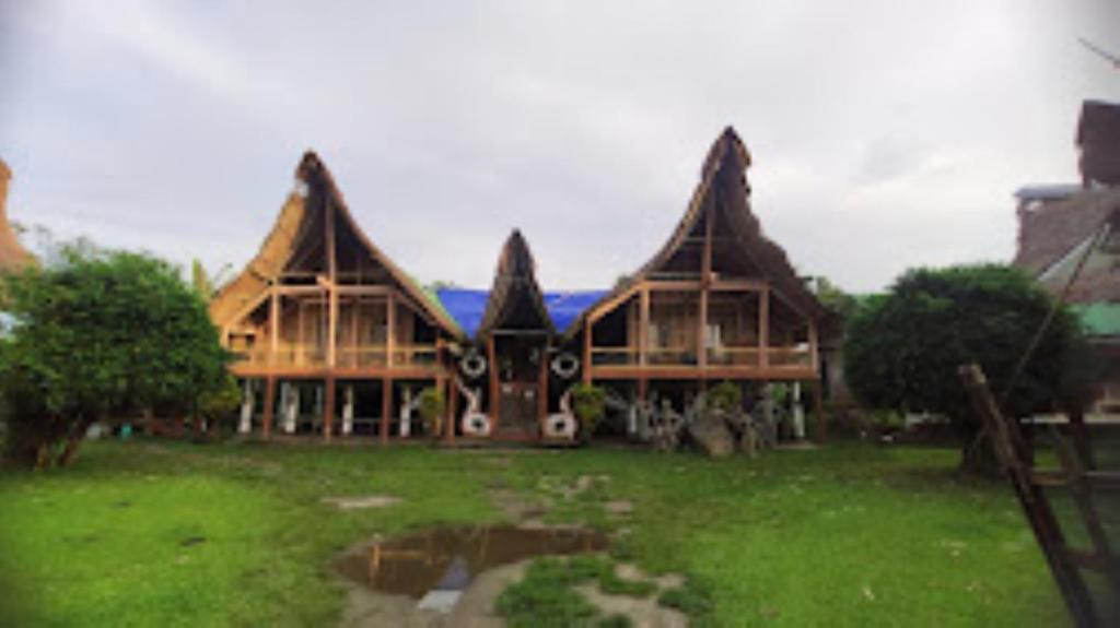 una gran casa de madera en un campo de hierba en Dekasang Majuli, en Majuli